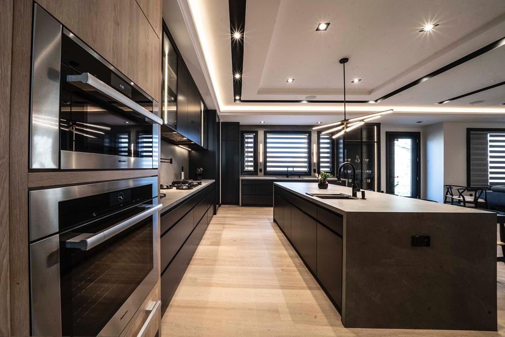 Galley view of dark modern kitchen with built-in ovens and stone island — Wynne project