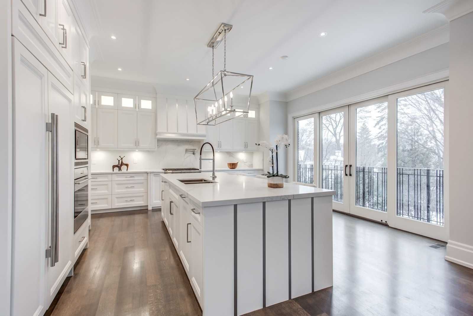 White kitchen with island overlooking garden doors