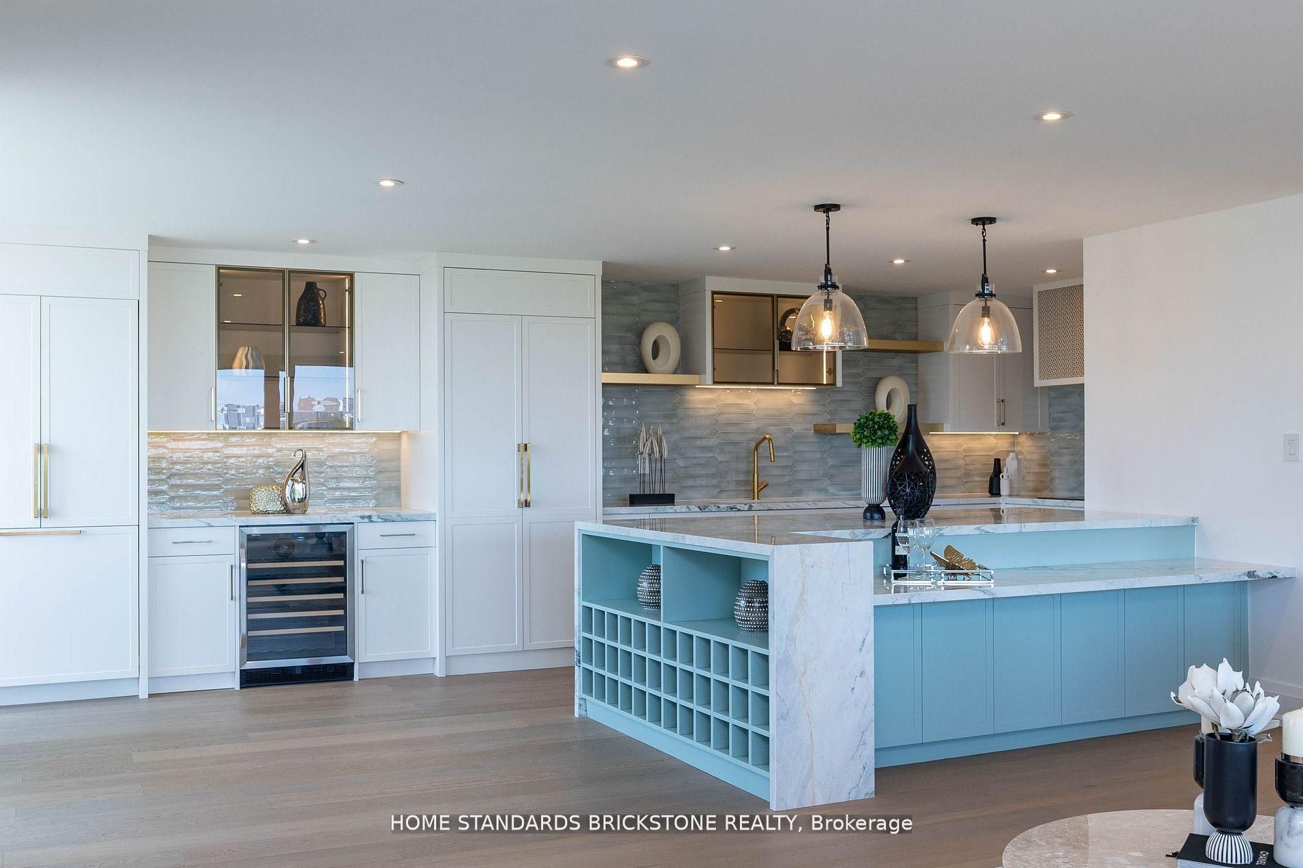 White shaker kitchen with aqua waterfall island, built-in wine cubbies and glass pendants