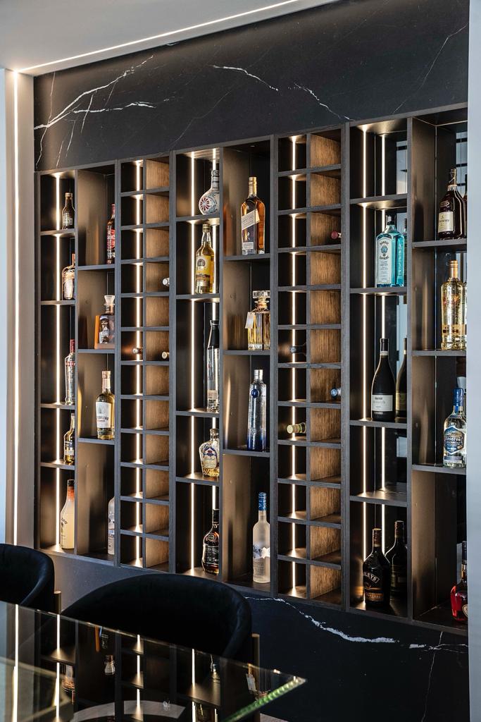 Backlit bar and wine display with black marble and brass shelving — Wynne project