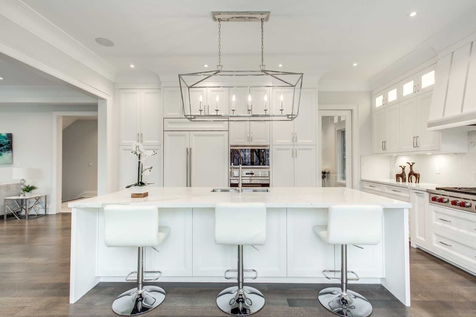 White kitchen with large island, chrome pendant and bar stools
